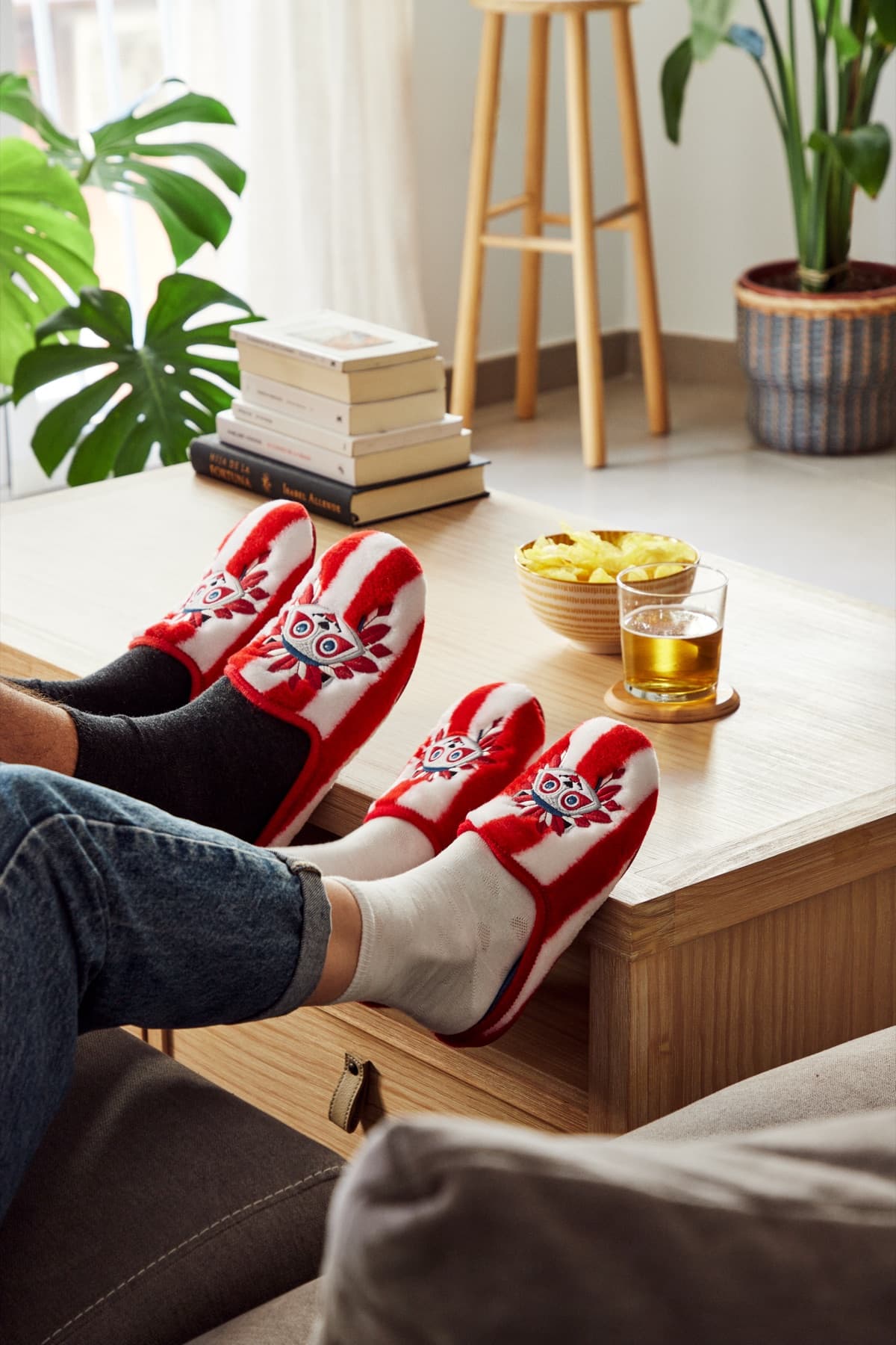 Padre e hijo en el sofá, ambos con zapatillas de casa oficiales del Atlético de Madrid